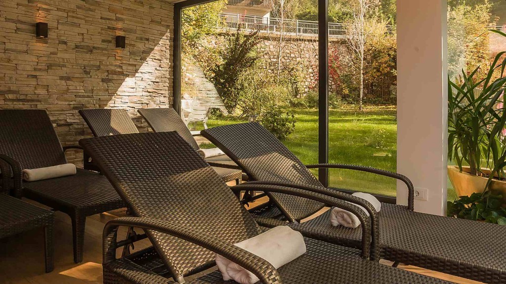 A serene relaxation area featuring comfortable lounge chairs with soft towels, surrounded by large windows that provide a view of lush greenery outside.